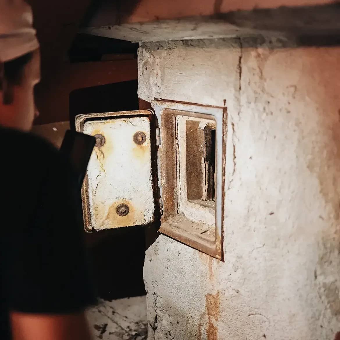 Rauchfangkehrer leuchtet in Kehrtürchen am Dachboden