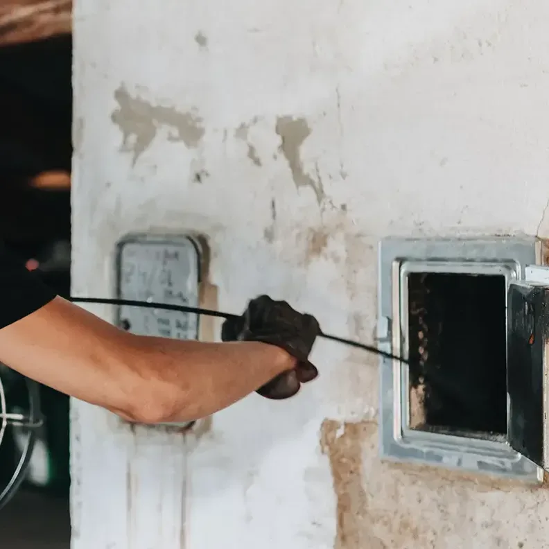 Rauchfangkehrer beim Kehren vom Dachboden aus